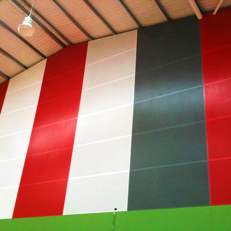 Painted perforated acoustic wood wall panels installed in a school sports hall for reverberation control and noise reduction